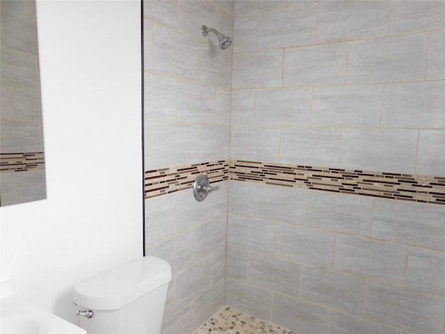 bathroom with a tile shower and toilet