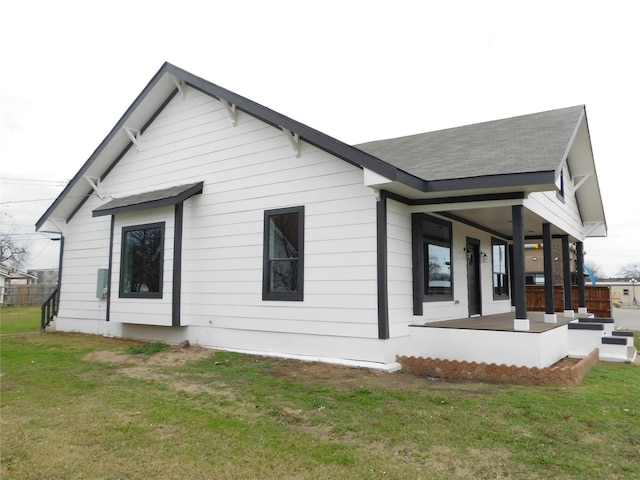 back of house featuring covered porch and a yard