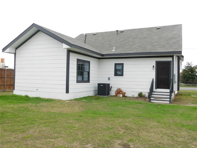 back of property with central AC and a lawn