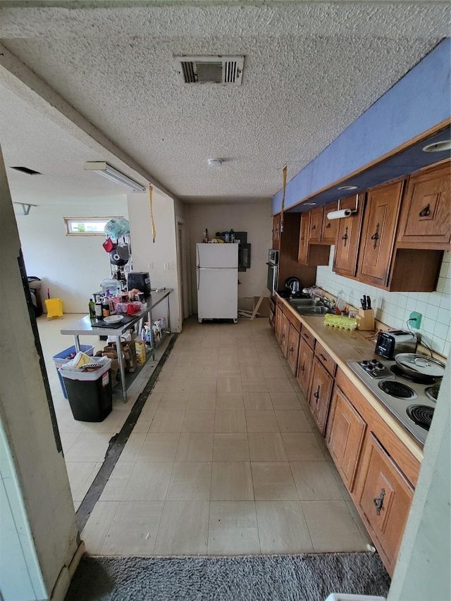 kitchen featuring cooktop, tasteful backsplash, wall oven, white fridge, and a textured ceiling