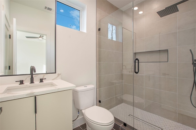 bathroom with ceiling fan, a shower with door, vanity, and toilet