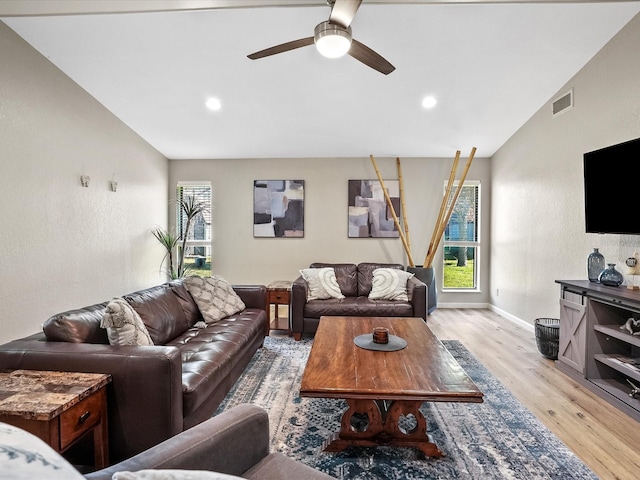 living room with ceiling fan, lofted ceiling, and light wood-type flooring