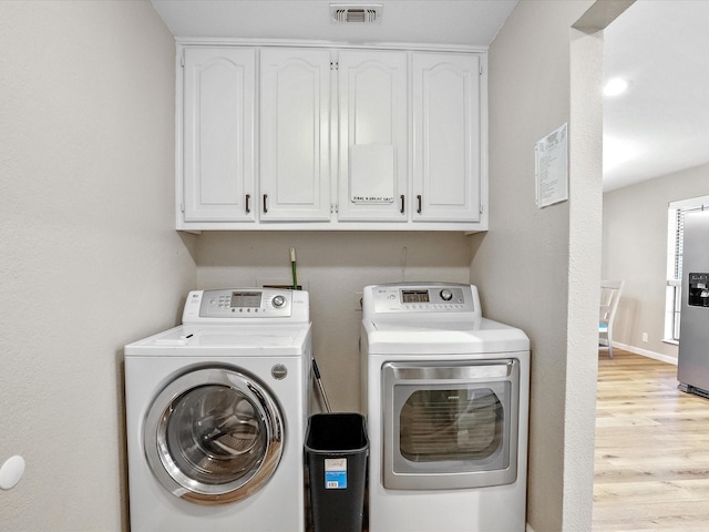 washroom with cabinets, separate washer and dryer, and light hardwood / wood-style flooring