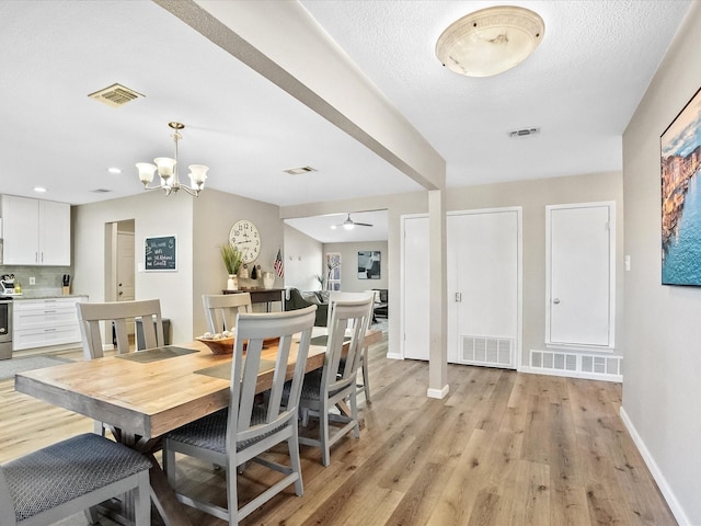 dining room with a textured ceiling, light hardwood / wood-style flooring, and ceiling fan with notable chandelier