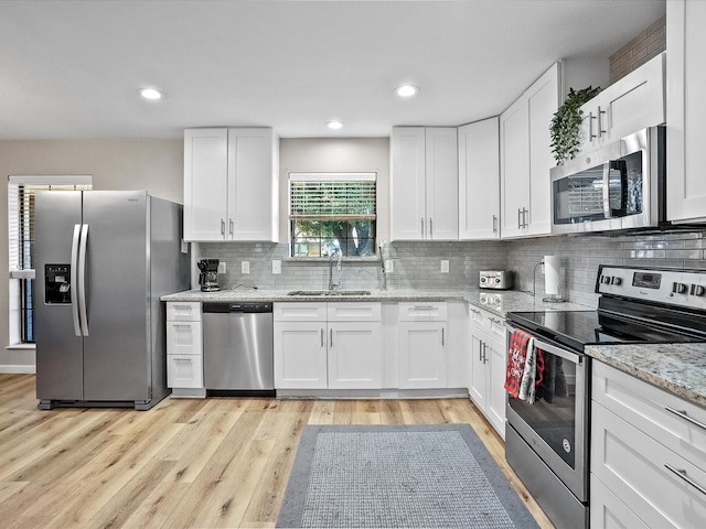 kitchen with light stone countertops, white cabinetry, sink, and appliances with stainless steel finishes