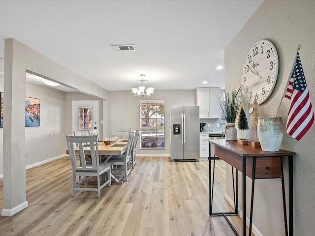 dining room with light hardwood / wood-style floors and an inviting chandelier