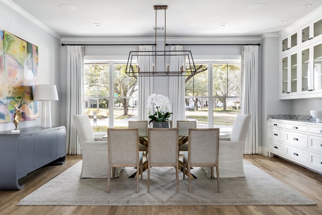 dining space featuring crown molding, a chandelier, and light hardwood / wood-style floors