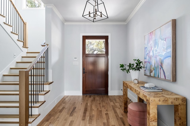 foyer entrance with an inviting chandelier, ornamental molding, and light hardwood / wood-style flooring