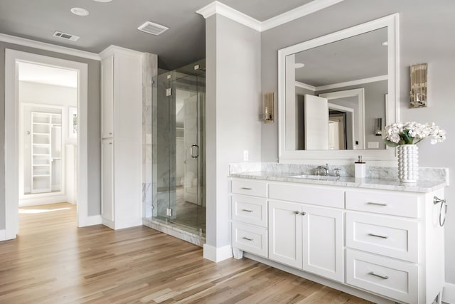 bathroom with wood-type flooring, vanity, an enclosed shower, and crown molding