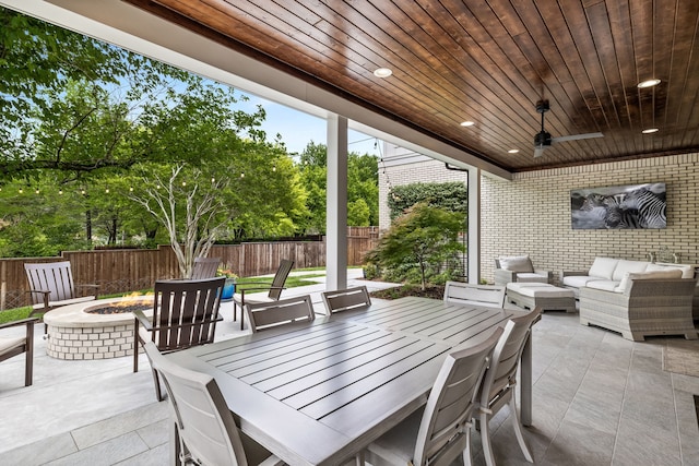 view of patio featuring ceiling fan and an outdoor living space with a fire pit