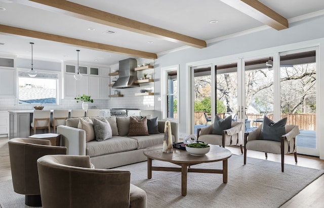 living room featuring beam ceiling, light hardwood / wood-style floors, ornamental molding, and a healthy amount of sunlight