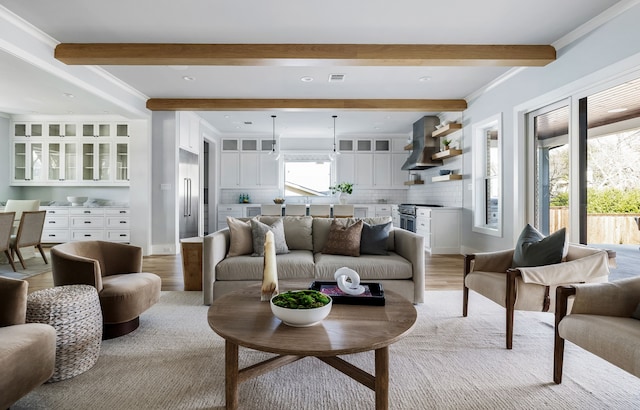 living room featuring beamed ceiling, crown molding, and light hardwood / wood-style flooring