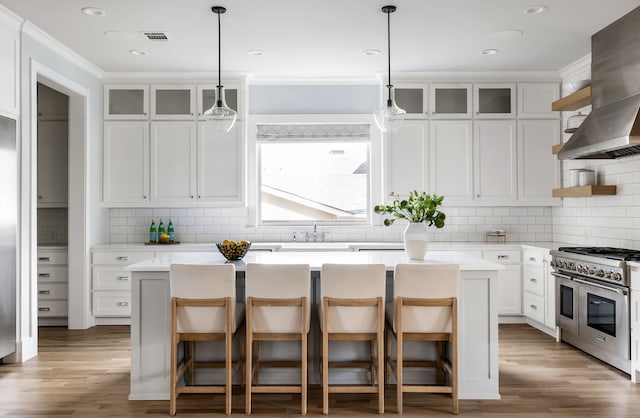 kitchen with a breakfast bar, white cabinets, double oven range, and a kitchen island