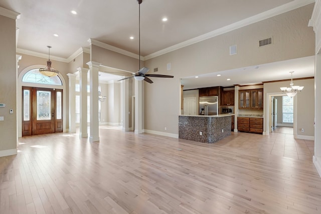 unfurnished living room featuring plenty of natural light, light wood-type flooring, crown molding, and ceiling fan with notable chandelier