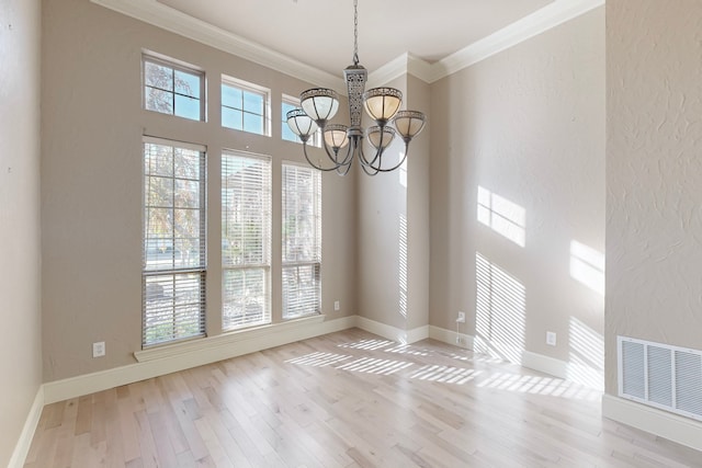 unfurnished dining area with a chandelier, light hardwood / wood-style floors, and ornamental molding