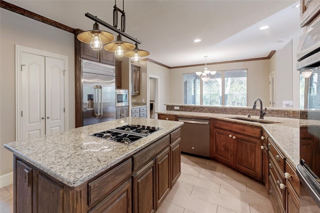 kitchen with an inviting chandelier, sink, hanging light fixtures, built in appliances, and a kitchen island