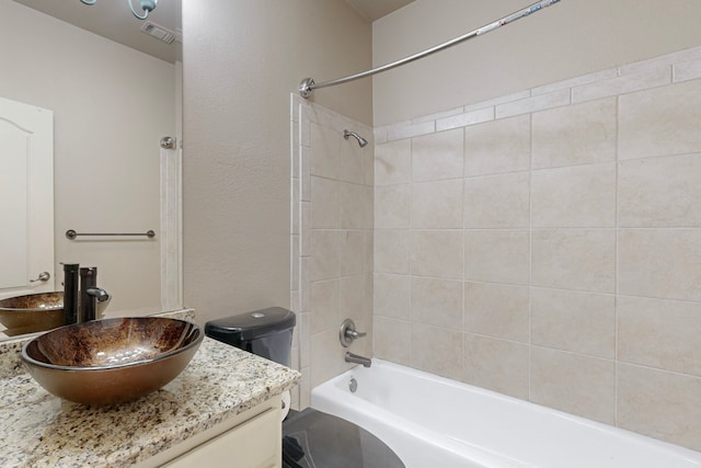 full bathroom featuring vanity, tiled shower / bath combo, and toilet