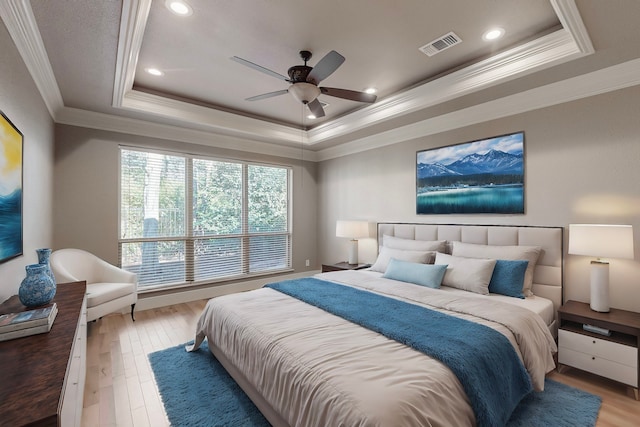 bedroom with ceiling fan, a raised ceiling, light wood-type flooring, and crown molding