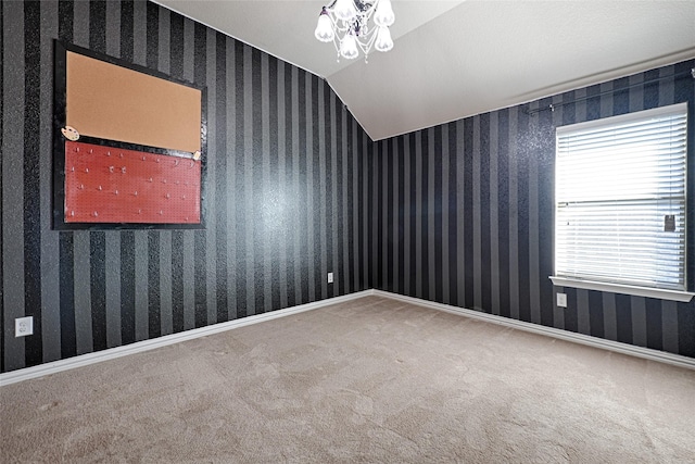 spare room featuring lofted ceiling, carpet, and a notable chandelier