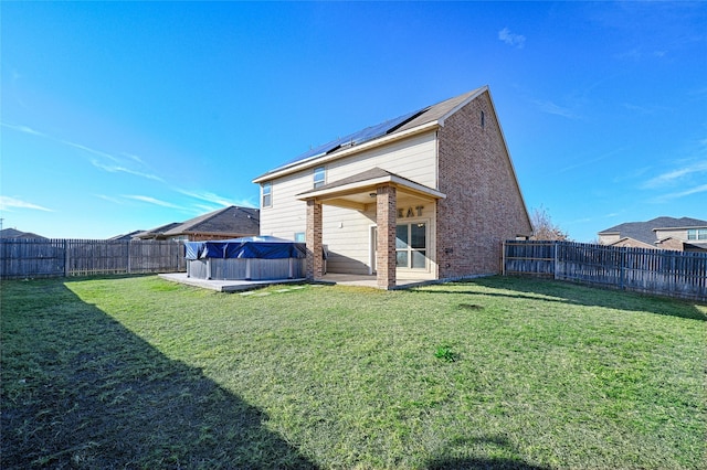 rear view of house with a patio, a yard, and solar panels