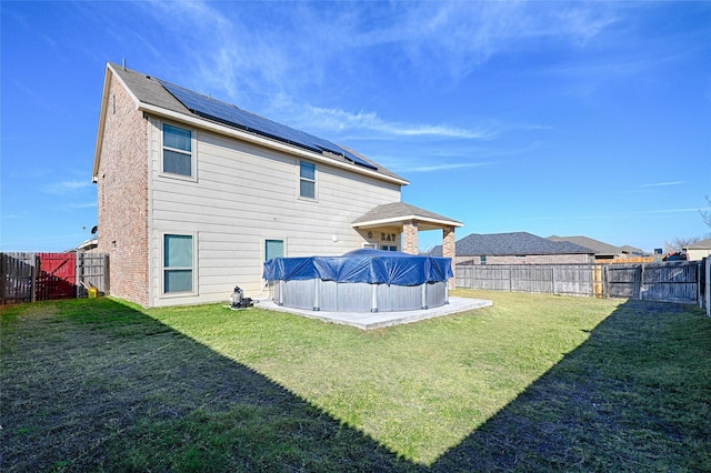 rear view of property with a yard and a covered pool