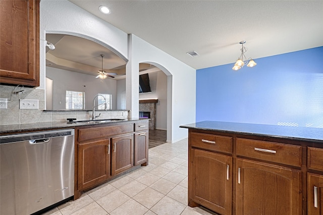 kitchen featuring ceiling fan with notable chandelier, decorative light fixtures, dishwasher, sink, and backsplash