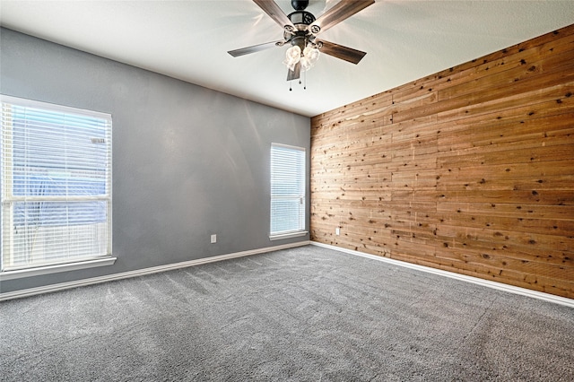 carpeted spare room with ceiling fan and wooden walls