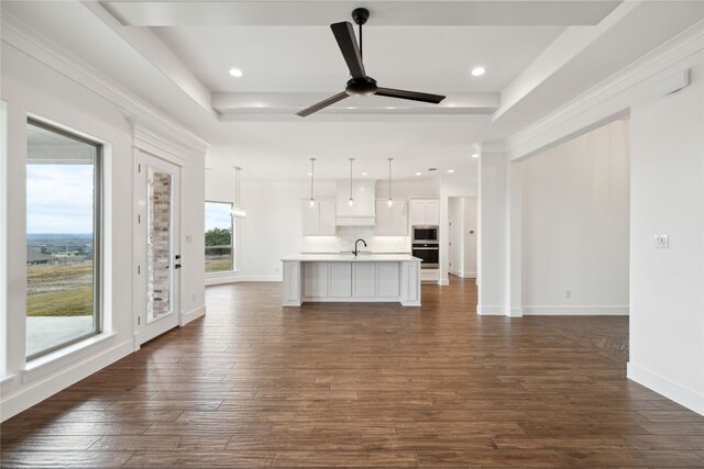 unfurnished living room with sink, crown molding, ceiling fan, dark hardwood / wood-style floors, and a tray ceiling