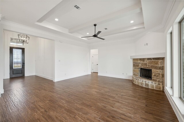 unfurnished living room with dark wood-type flooring, ceiling fan with notable chandelier, a stone fireplace, ornamental molding, and beam ceiling