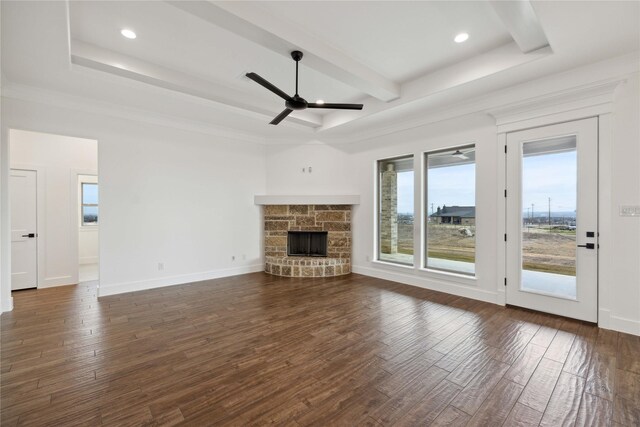 unfurnished living room featuring beamed ceiling, a stone fireplace, ceiling fan, and dark wood-type flooring