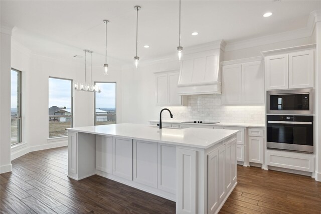 kitchen featuring white cabinets, oven, a kitchen island with sink, and custom exhaust hood