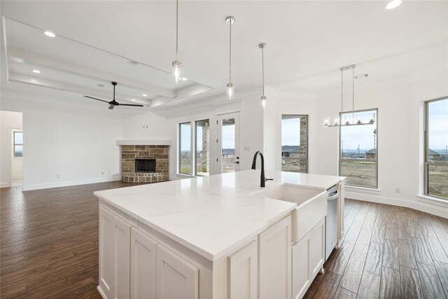 kitchen featuring dark hardwood / wood-style flooring, ceiling fan, decorative light fixtures, white cabinetry, and an island with sink