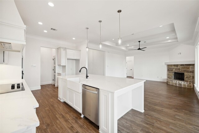 kitchen with dishwasher, a kitchen island with sink, a raised ceiling, hanging light fixtures, and white cabinetry