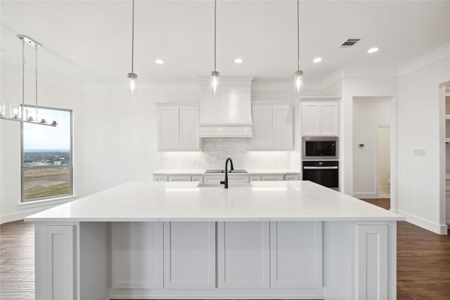 kitchen featuring white cabinets, a spacious island, hanging light fixtures, light stone countertops, and appliances with stainless steel finishes