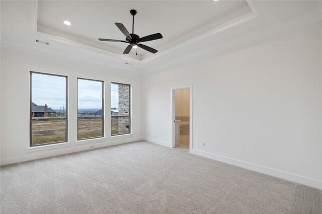 carpeted empty room with ceiling fan, a raised ceiling, and crown molding