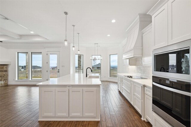 kitchen featuring white cabinets, decorative backsplash, pendant lighting, and a kitchen island with sink