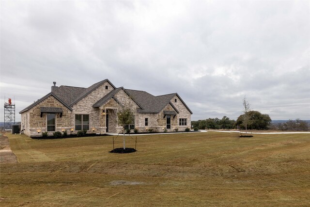 french country home featuring cooling unit and a front lawn