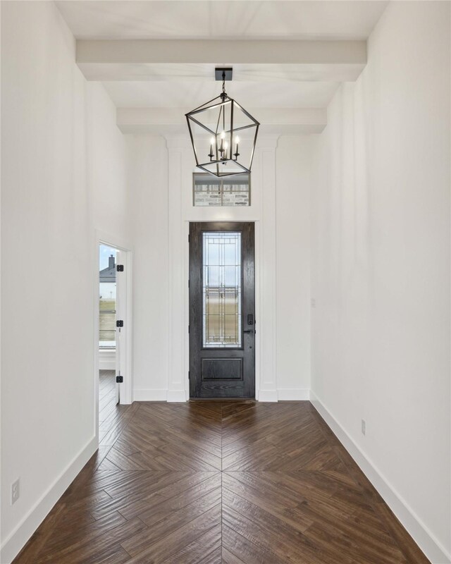 entryway with dark parquet flooring, beamed ceiling, and a chandelier