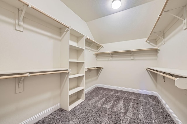 spacious closet featuring dark colored carpet and vaulted ceiling