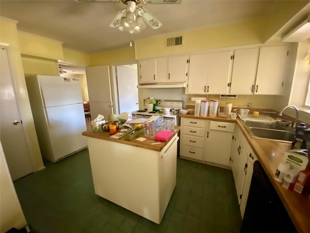 kitchen with white appliances, white cabinets, a center island, sink, and ceiling fan