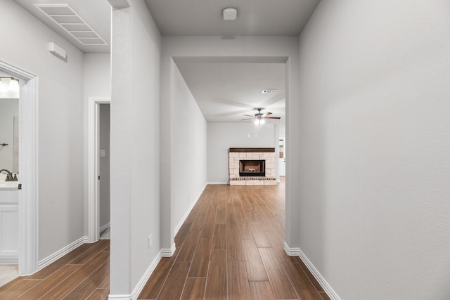 hallway with dark wood-style floors, baseboards, and visible vents