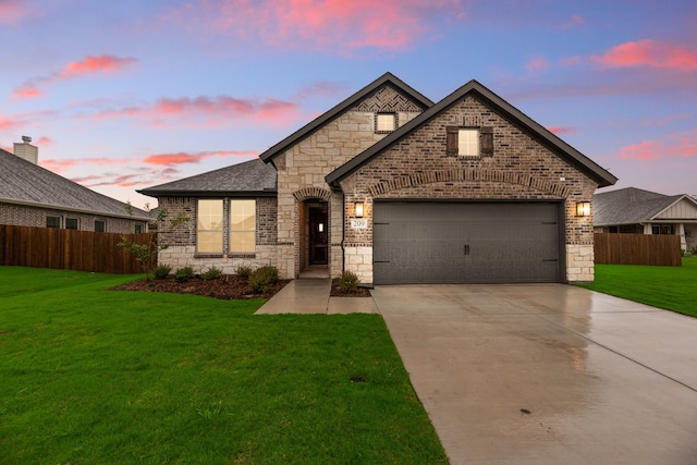 french country style house featuring a front yard, driveway, stone siding, brick siding, and fence