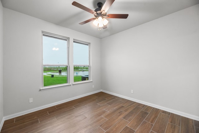 spare room featuring a ceiling fan, baseboards, and dark wood finished floors