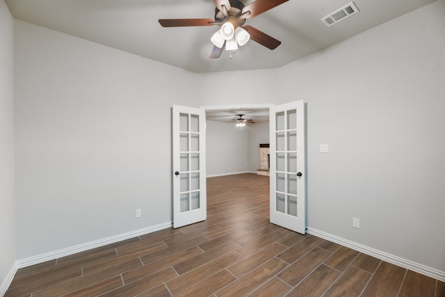 empty room with french doors, ceiling fan, dark wood finished floors, and baseboards