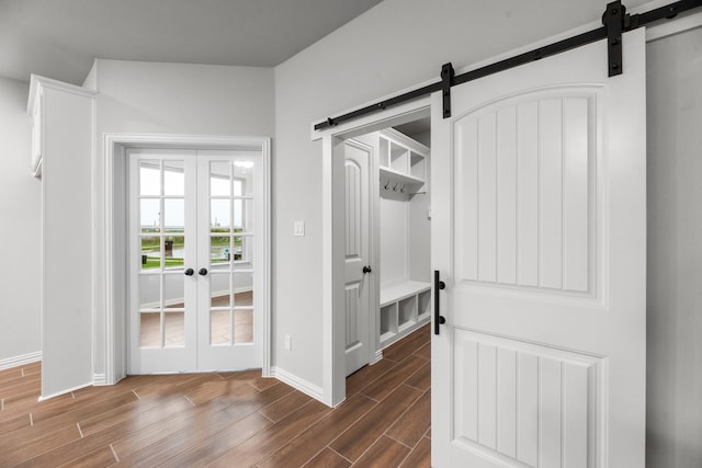 interior space featuring baseboards, a barn door, french doors, and dark wood-type flooring