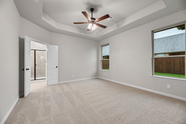 spare room with baseboards, light carpet, ceiling fan, and a tray ceiling