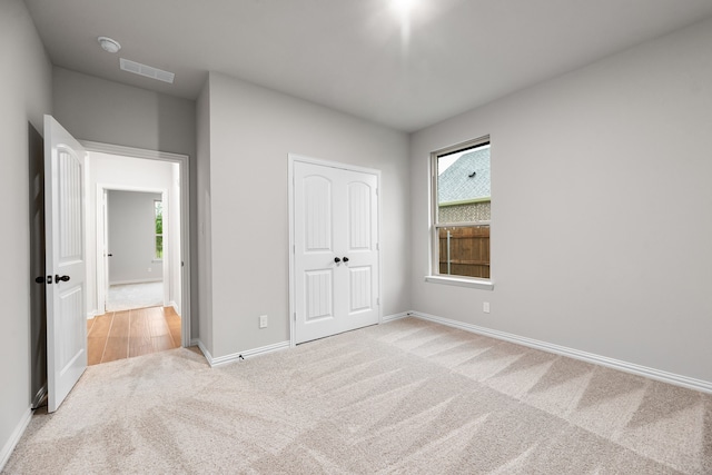 unfurnished bedroom featuring multiple windows, visible vents, carpet flooring, and baseboards