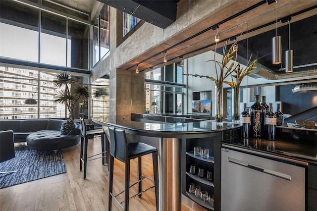 bar with hardwood / wood-style floors, stainless steel dishwasher, and a towering ceiling