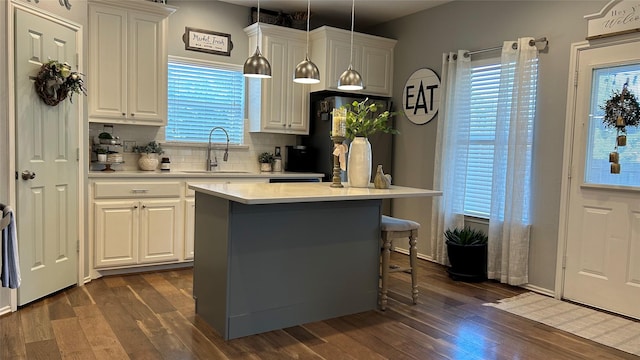 kitchen with decorative light fixtures, a center island, sink, and white cabinets