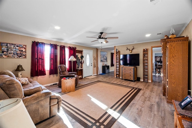 living area with ceiling fan, crown molding, and wood finished floors